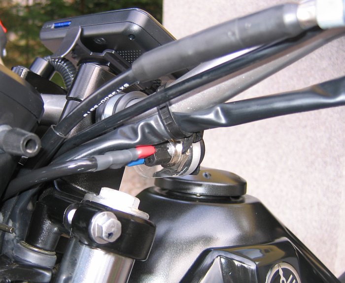 Yamaha Tricker mit am Lenker montiertem Medion Navi PNA. Der Schwanenhals ist zu schwach ausgelegt. Das Navi muß im Betrieb durch eine Plastikhülle gegen Regen geschützt werden. Auch zu sehen ist die Touratech Bordnetzsteckdose.